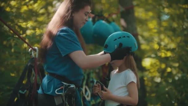 Instruktorka zakłada kask ochronny dla dziewczynki na przygodę z liną — Wideo stockowe