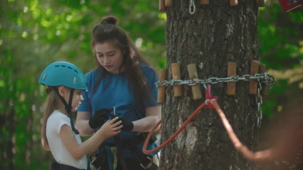 Instruktorin erklärt einem kleinen Mädchen, wie man einen Versicherungshaken am Seil benutzt — Stockvideo