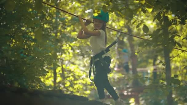 Holčička, co chodí po mostě a drží se u provazu- zábavní atrakce v lese — Stock video