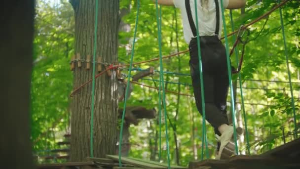 Frau überquert eine Seilbrücke - eine Attraktion im Wald — Stockvideo