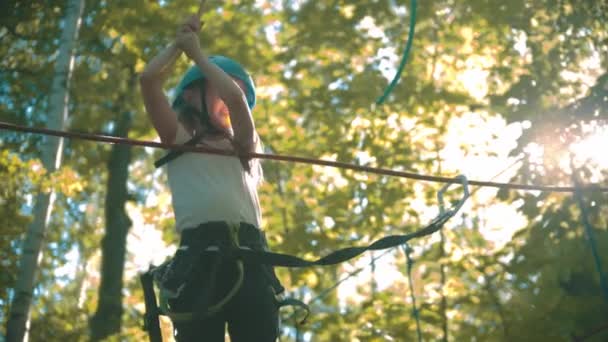 Uma menina atravessando a ponte de corda na floresta — Vídeo de Stock