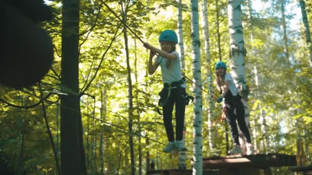 Junge Frau und ihre Tochter überqueren das Seil auf einer Attraktion im Park — Stockvideo