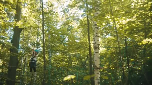 Una bambina che scende sul cavo assicurativo della sua cintura - attrazione di intrattenimento ponte di corda nel parco — Video Stock