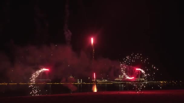 ดอกไม้ไฟสีแดงบนชายหาดในเวลากลางคืน การเคลื่อนไหวหมุนและระเบิดขึ้น — วีดีโอสต็อก
