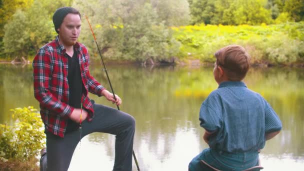 Fishing on nature - big brother gives a fishing rod to his little brother — Stock Video