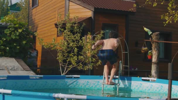 Giovane uomo che salta in piscina dal retro — Video Stock