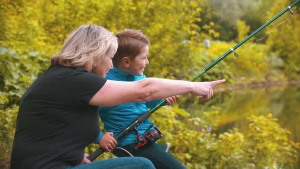 Un niño pequeño con su madre en la pesca en la naturaleza - niño girando la ruleta — Vídeos de Stock
