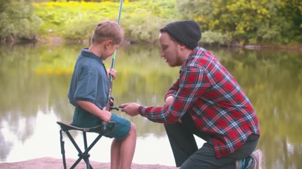 Pesca en la naturaleza - hermano mayor enseñando a su hermano pequeño a pescar — Vídeo de stock