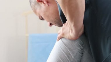 Genç bir kadın kanepede uzanıyor ve masaj uzmanı vücuduna baskı yapıyor - bacaklarını büküyor.