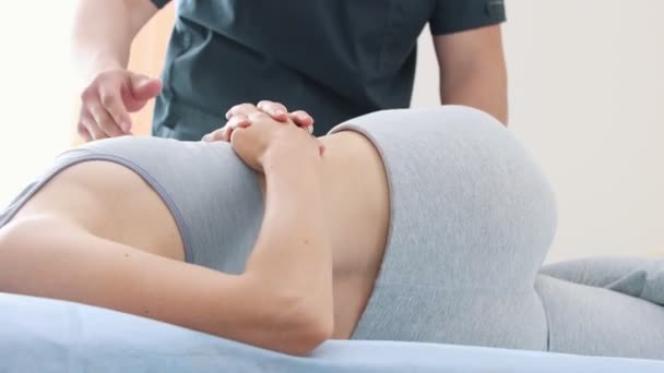 Jonge vrouw liggend op een bank op haar kant en de massagist drukken op haar lichaam — Stockvideo