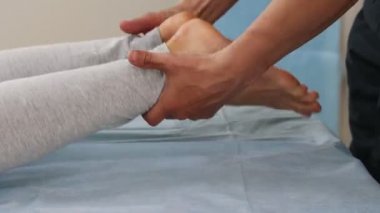 Osteopatik tedaviden geçen bir kadın, ayaklarına masaj yapıyor.