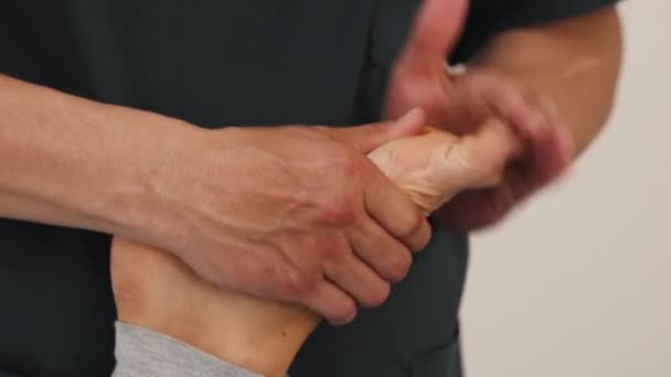 Donna che subisce un trattamento osteopatico massaggiatrice massaggiando le dita dei piedi — Video Stock