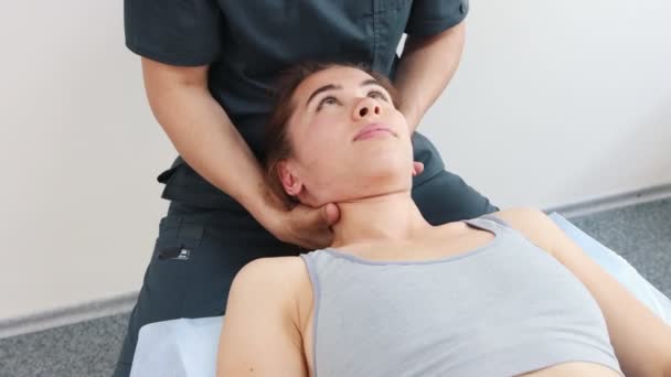 Massageassistentin arbeitet mit jungen Frauen im Nacken, während sie auf einer Couch liegt — Stockvideo