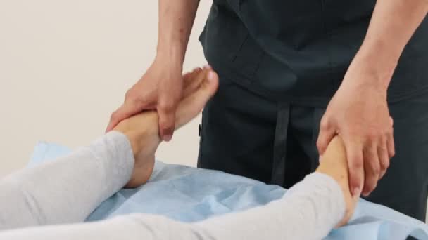Nainen, jolla on osteopaattinen hoito - hieroja lämmittää jalkojaan — kuvapankkivideo