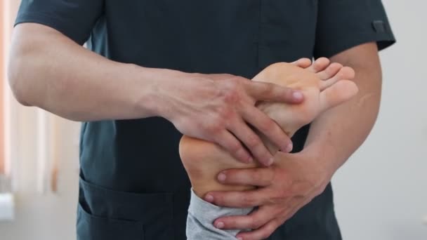 Žena podstupující osteopatickou léčbu - masagistka si ohřívá nohy a kotník — Stock video