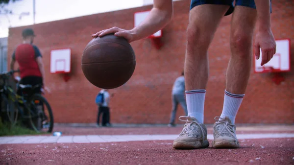 Junger Mann auf Basketballplatz schlägt auf den Ball ein — Stockfoto