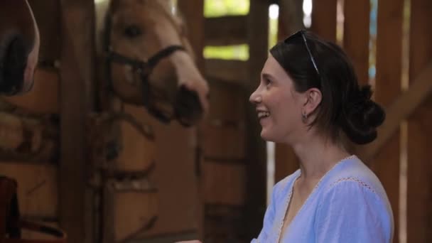 Leende lycklig kvinna mata häst ett äpple i paddock — Stockvideo