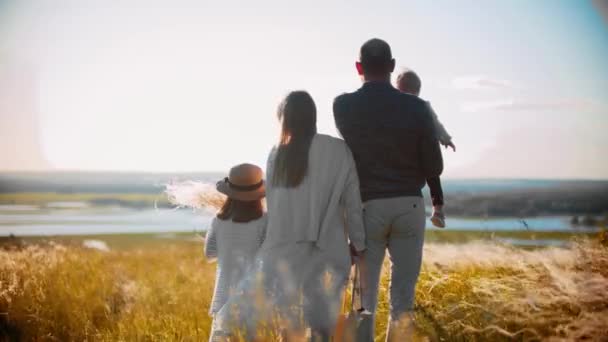 赤ん坊と女の子が畑の上に立って遠くを見ている若い家族 — ストック動画