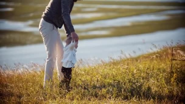 Jeune père avec son bébé sur le terrain - apprendre à sa fille à marcher — Video