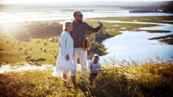 Молодая семья стоит на пшеничном поле - отец обнимает жену и разговаривает с ней — стоковое видео