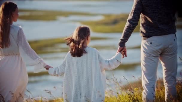 Genç bir aile buğday tarlasında duruyor ve nehre bakarken el ele tutuşuyorlar. — Stok video