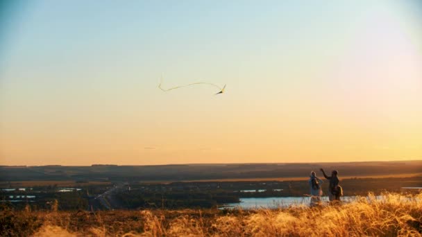 Jeune famille jouant avec cerf-volant sur le terrain au coucher du soleil - père tenant la corde de cerf-volant — Video