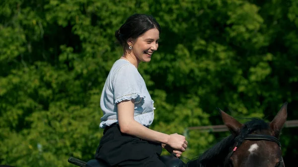 Ung leende kvinna i blå skjorta rider en häst — Stockfoto
