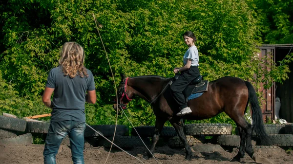 Mujer joven con camisa azul aprendiendo a montar a caballo — Foto de Stock