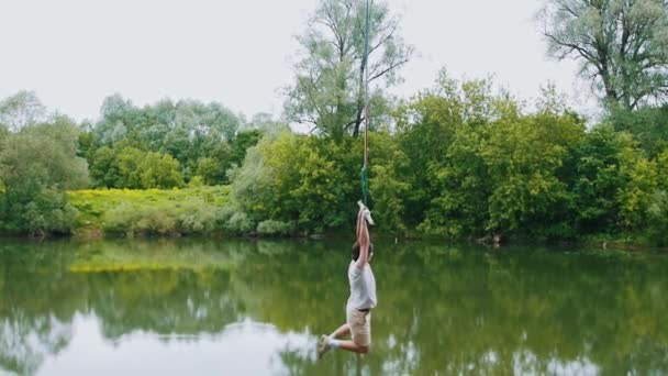 Young man flying above the water holding by the bar — Stock Video