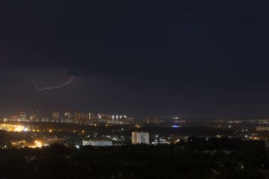Gecenin karanlığında şimşekler çakıyor. Şehrin üstündeki bulutlu gökyüzü.