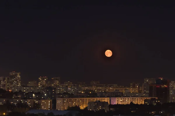 Luminosa luna gialla nel cielo scuro quasi nero sopra la città — Foto Stock