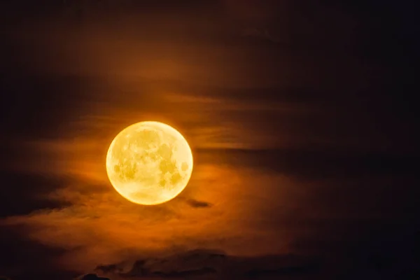 Lua amarela brilhante no céu escuro e ilumina as nuvens — Fotografia de Stock