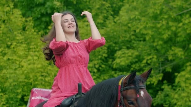 Ung kvinna i rosa klänning sitter på en häst — Stockvideo