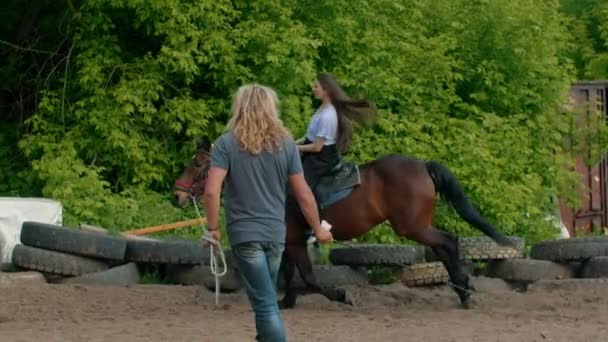 Jovem mulher feliz com cabelos longos em camisa azul montando um cavalo — Vídeo de Stock