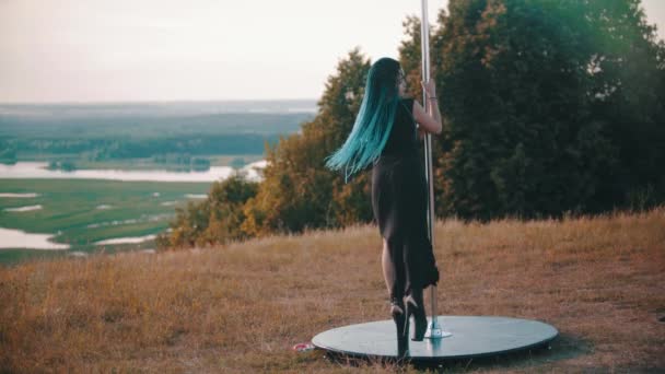 Vrouw met blauwe vlechten op hoge hakken dansen door de paal buiten — Stockvideo