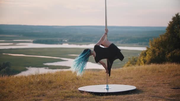 Femme avec des tresses bleues sur des talons hauts dansant près du poteau à l'extérieur sur la nature - tournant sur le poteau — Video