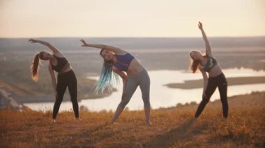 Sahada üç genç kadın antrenman yapıyor.