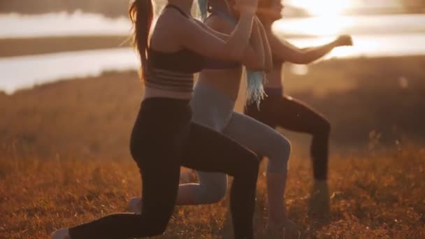 Три молодые женщины делают аэробные упражнения на закате на открытом воздухе - выпады — стоковое видео
