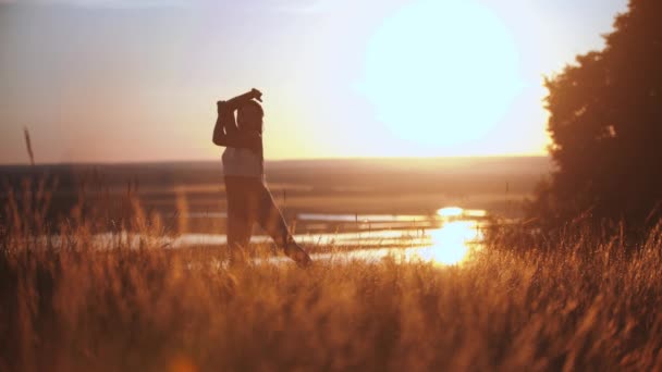 Mulher com tranças longas dançando lentamente no campo de pôr do sol — Vídeo de Stock