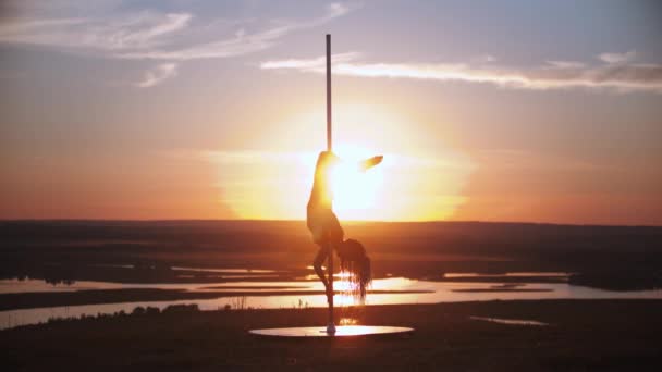 Jovem mulher segurando pelo poste de dança e de cabeça para baixo no pôr do sol — Vídeo de Stock