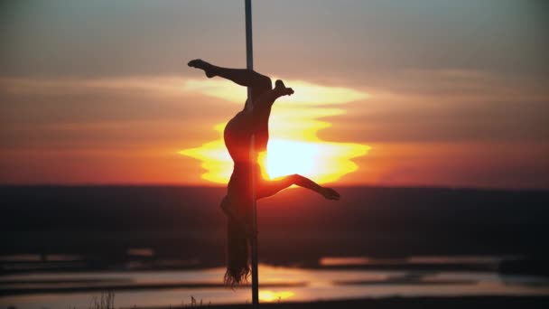 Jeune femme tenant par le poteau de danse avec ses jambes — Video