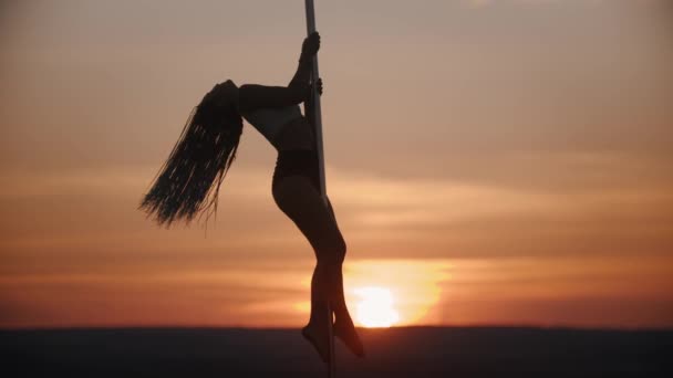 Mujer joven con trenzas largas bailando en el poste al atardecer — Vídeos de Stock