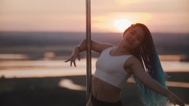 Jeune femme avec de longues tresses filant près du poteau le soir du coucher du soleil — Video