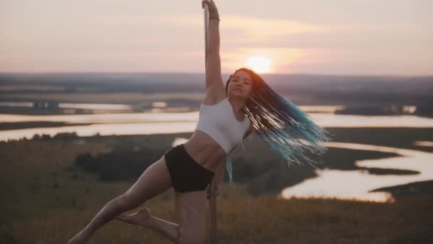 Jovem com longas tranças azuis girando pelo poste na noite do pôr do sol — Vídeo de Stock