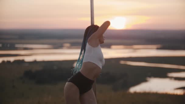 Young woman stripper with long blue braids dancing by the pole on sunset evening — Stock Video