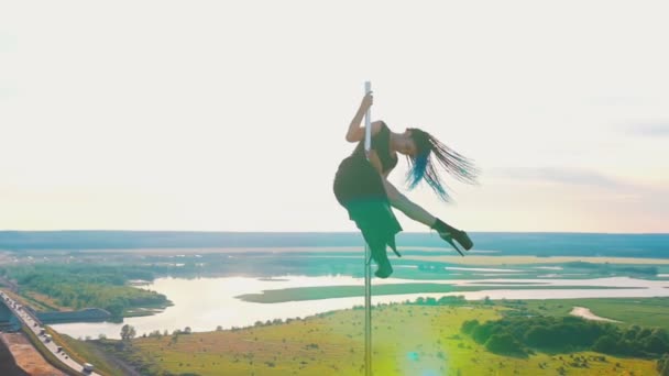 Pole dance sulla natura donna attraente con lunghe trecce blu in abiti neri in posa sulla parte superiore del palo — Video Stock