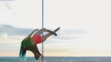 Doğada direk dansı. Uzun mavi örgülü çekici kadın direğin üzerinde dans ediyor.