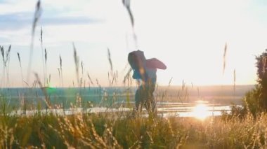 Güneş batan buğday tarlasında dans eden uzun örgülü bir kadın.
