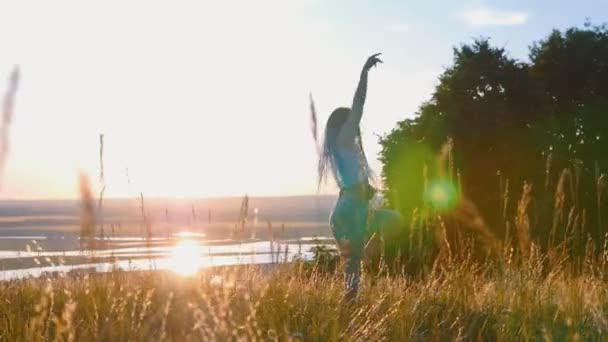 Nő hosszú copfokkal lassan táncol a naplemente búzamezőn — Stock videók