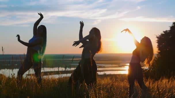 Aeróbicos en la naturaleza - tres mujeres jóvenes bailando al atardecer — Vídeo de stock